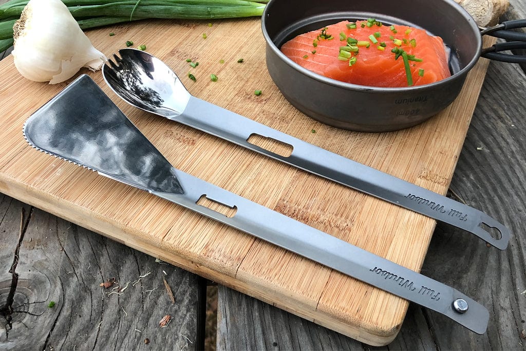 The Splitter Titanium Multi Tongs on a chopping board, ready to be used for camp cooking